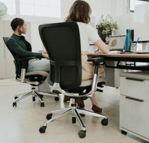 Two women at their desk chairs working