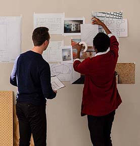 People taping paper with office designs on the wall